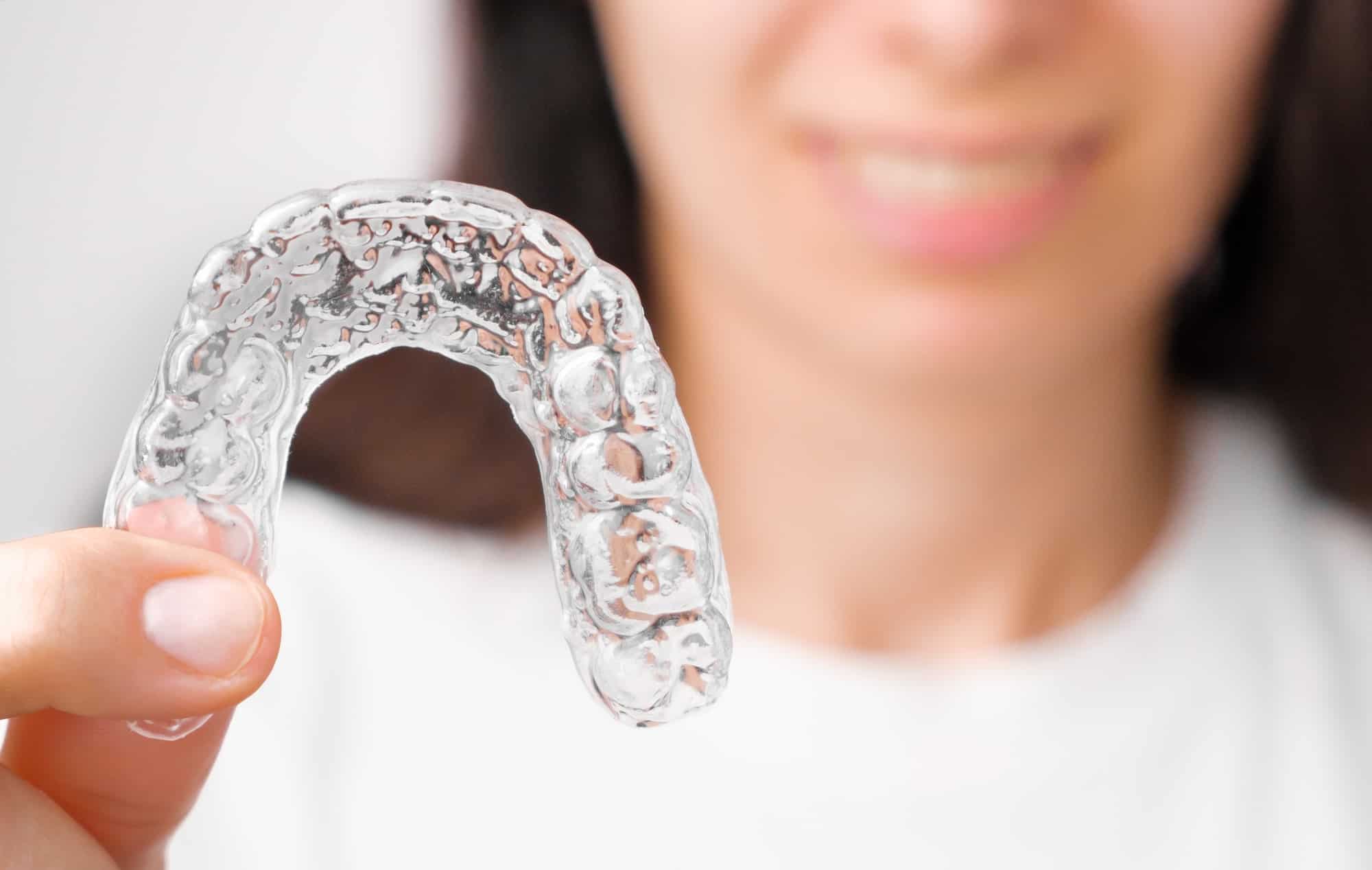Close up orthodontic transparent aligner in womans hand. Removable braces