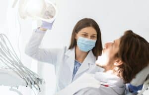 Dentist in mask turning on lamp before making check up